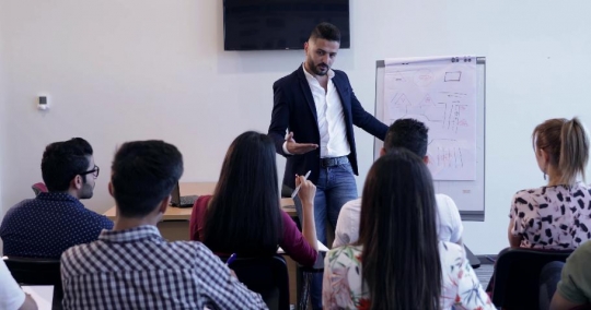 Woman raises her hand in class to ask a question |-