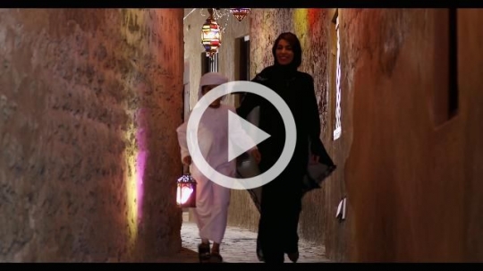 Arab woman and young kid walking through the pathway decorated by Ramadan Lanterns|