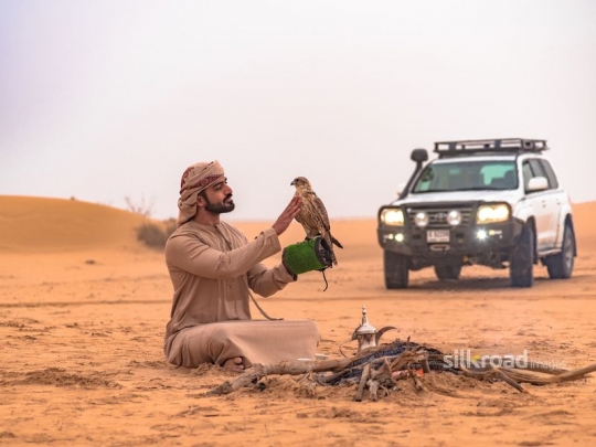 Man carrying falcon in the desert