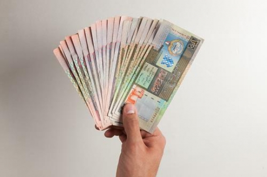 hands with kuwaiti dinars