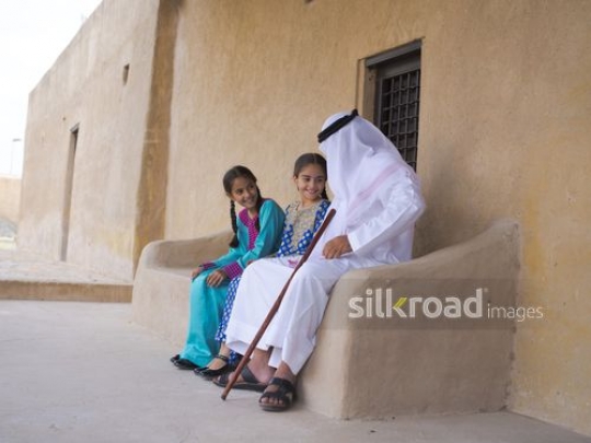 Old man sitting outside with grandchildren|-