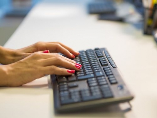 Woman typing on the keyboard at her desk|