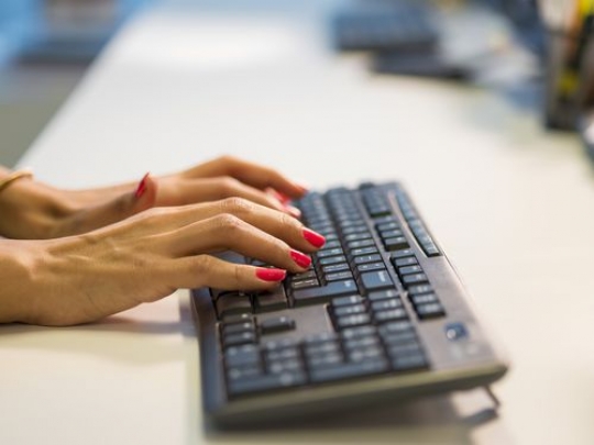 Business woman sitting by her desk typing on the keyboard|