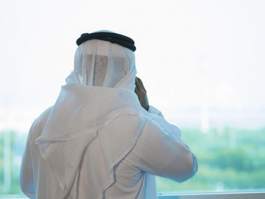 Arab man making a phone call by the window|-