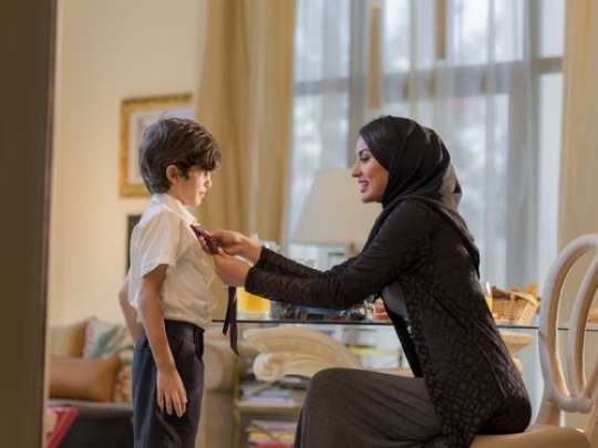 Arab woman helping the young boys tie for school|-