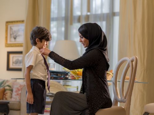 Arab mother fixing her sons tie for school|-