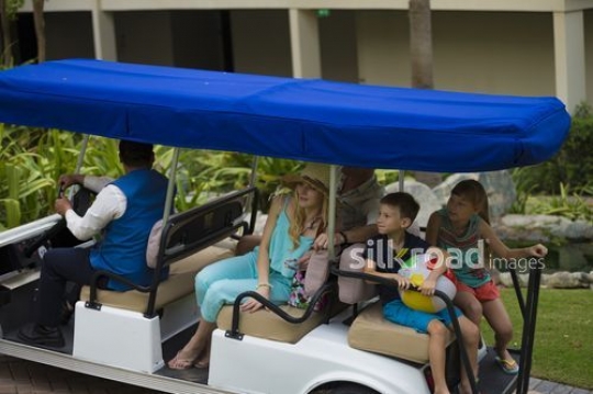 Western couple with their kids on a golf cart|-