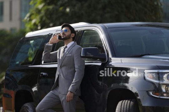 Businessman standing next to the car using his mobile|-