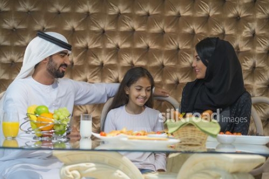 Middle Eastern parents sitting with daughter for breakfast|