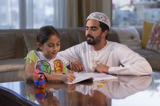 Arabian man helping the young girl with his homework |-
