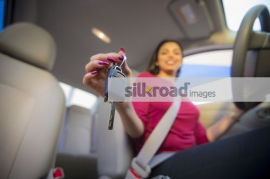 Arab woman smiling inside the car with the key in hand|