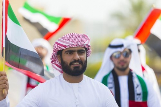 Arab man carrying a UAE flag celebrating National Day|
