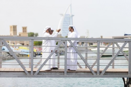 Arab men standing by the dock talking to each other|