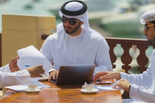 Arab men dressed in the UAE traditional attire during a business meeting|