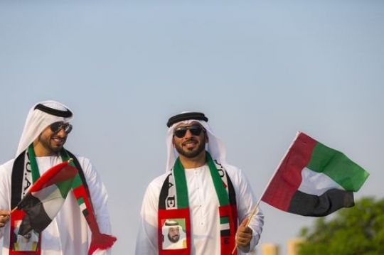 Middle eastern men dressed in the UAE traditional attire celebrating National day|-