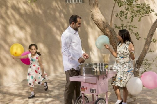 Arab man offering cotton candy to the girl|-