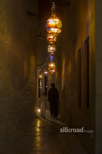 Middle Eastern mother and son walking together through the pathway decorated by Ramadan Lanterns|-