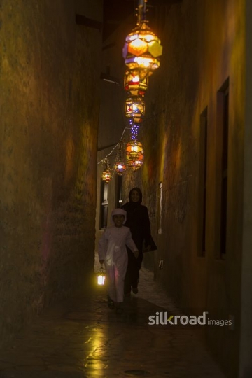 Arab woman and boy walking through the pathway decorated by Ramadan Lanterns|-