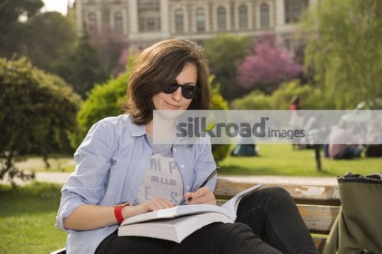 Student sitting on the bench reading a book|