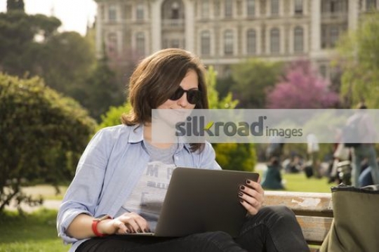 Woman sitting on the bench using the laptop |