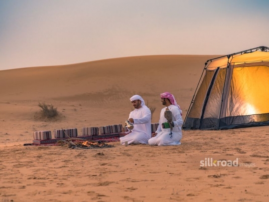 Men drinking coffee outside tent