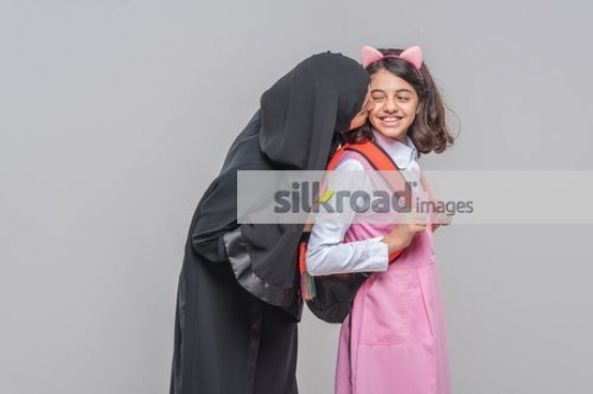 Arab woman kissing the young girls cheek|