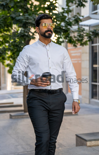 Man Walking Between Modern Buildings with Coffee Cup in Al Abdali Boulevard