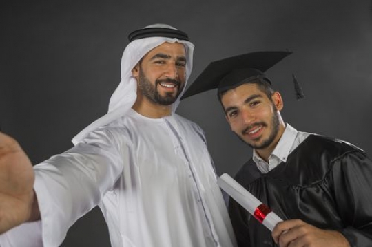 Proud father taking a selfie with his son graduating