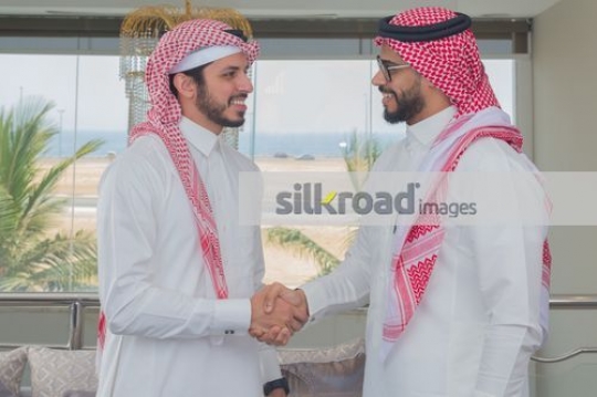 Middle Eastern employees shaking hands|