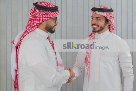 Middle Eastern Businessmen dressed in the traditional attire shaking hands|
