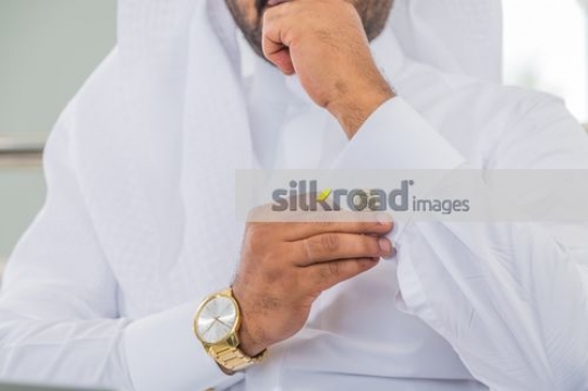Man fixing the cufflink on his kandoura|