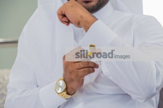 Middle Eastern man fixing his cufflink on the kandoura|
