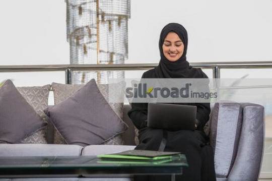 Business woman sitting on the couch working from the laptop|