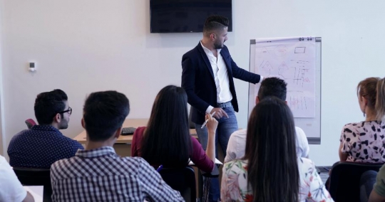 Professor teaching the students and the woman raises her hand|-