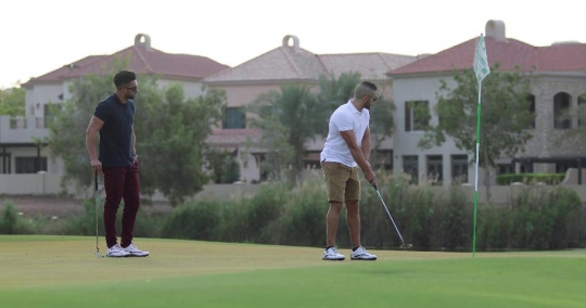 Middle Eastern man playing golf with his friend|-