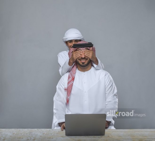 Boy covering eyes of father