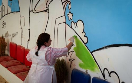 fat girl painting the wall of a kindergarten