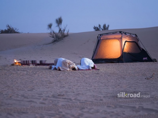 Men praying in the desert