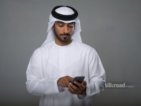 Arabian man sending a text message|