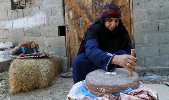 portrait of a palestinian woman turning a millstone