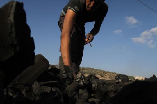 A man picking up charcoal 