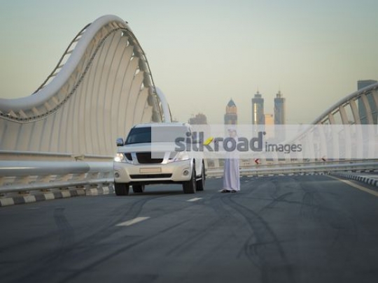 Arab man dressed in the traditional attire talking on the phone|