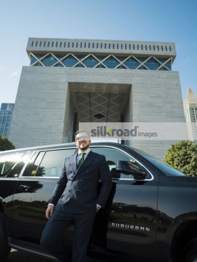 Western Businessman leaning on the car smiling|