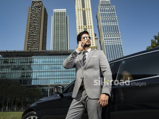 Businessman wearing his sunglasses using his phone|-