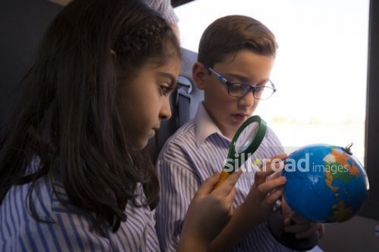 Middle Eastern kids looking at the globe together|-