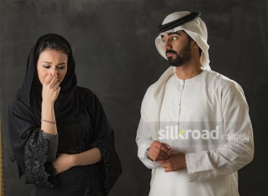 Middle Eastern woman upset standing next to the Middle Eastern man|