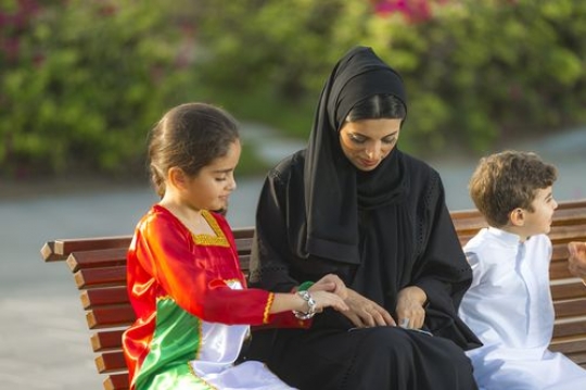 Mother helping her young daughter with her jewellery |-