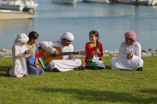 Middle eastern teenager playing the guitar and the rest are singing along|-
