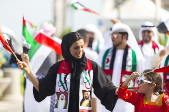Group of people carrying the UAE flag during a National Day Parade|