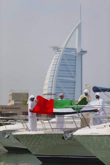 Arabian men attaching the UAE flag to the yacht to celebrate National Day|